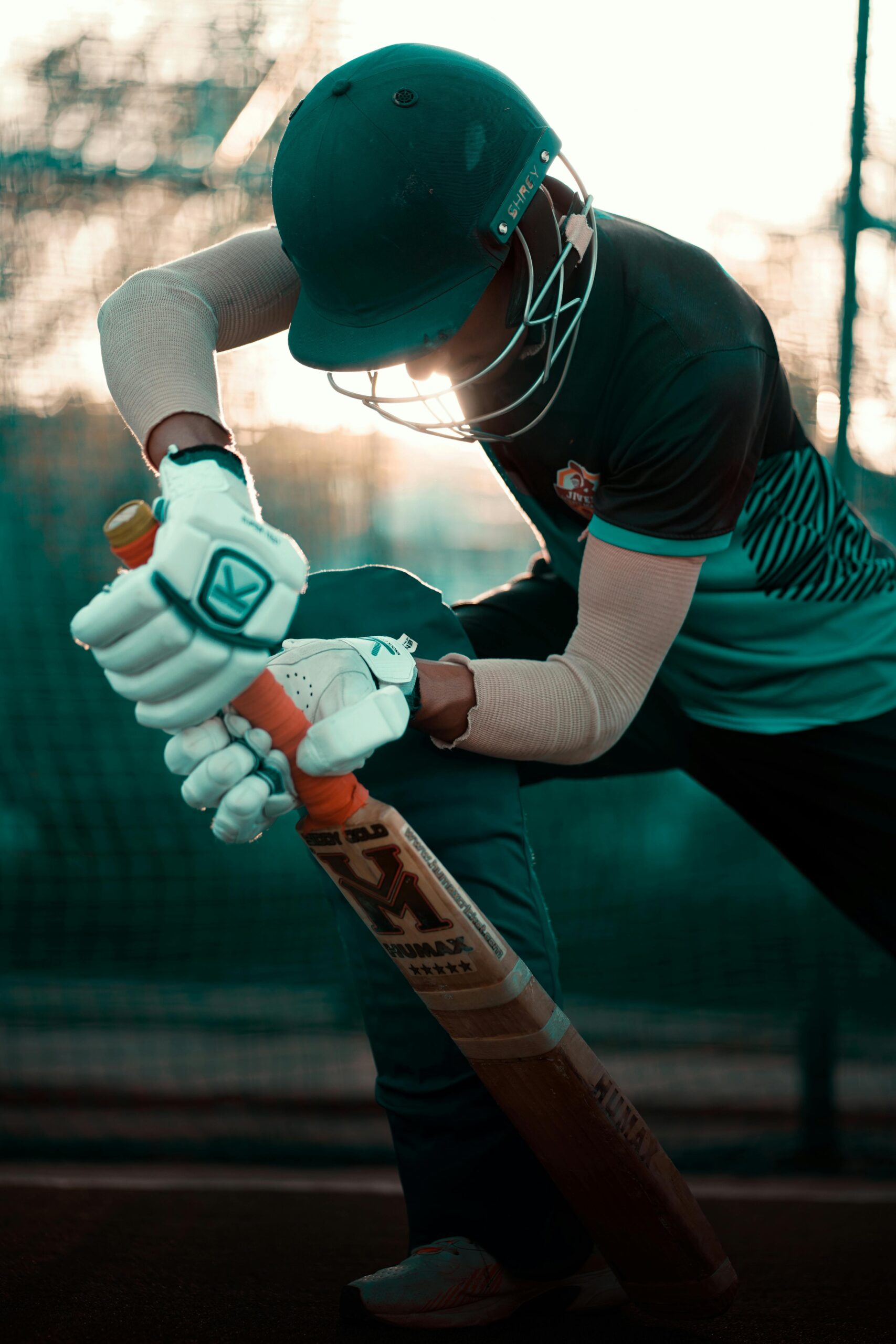 Side profile of a cricketer practicing batting technique at sunset.