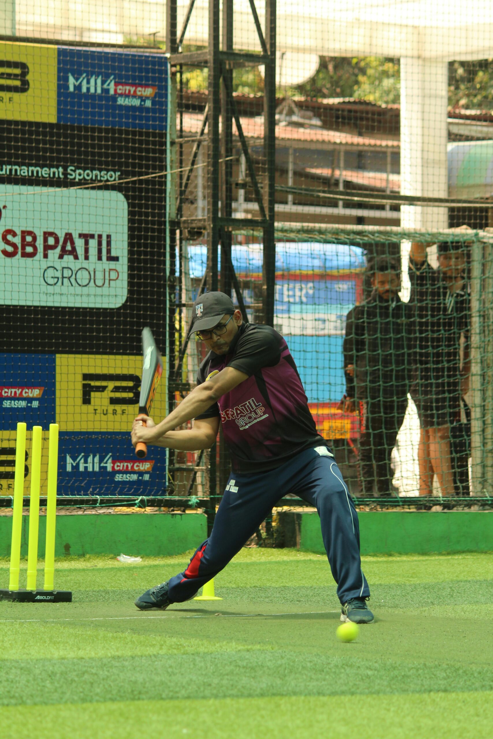 Cricketer in action swinging bat on an outdoor turf field in India.